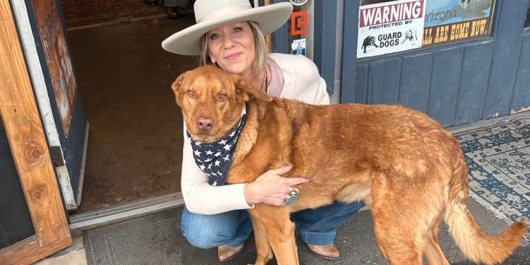 Kristen with her arm around Francis the dog by the front entrance of Cowgirl Country Antiques