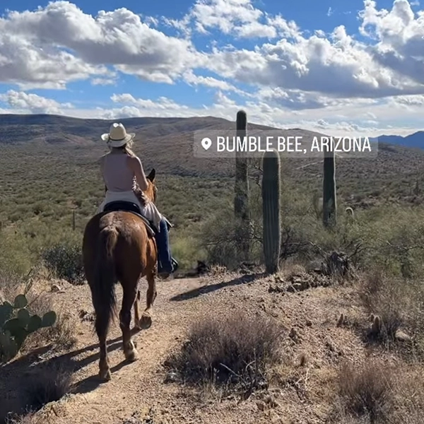 cowgirl on horseback through Sanoran Desert in Arizona