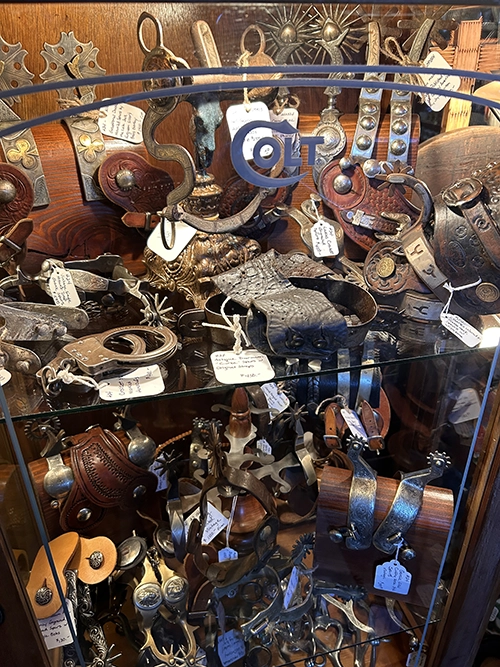 display table full of antique spurs and cowboy gear